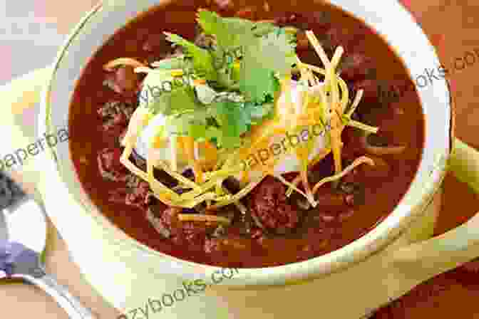 A Close Up Of A Bowl Of Chili Garnished With Fresh Cilantro, Sour Cream, And Grated Cheese, Showcasing The Art Of Enhancing Flavors With Finishing Touches. Chili Recipes Made To Perfection: Brand New Chili Recipes